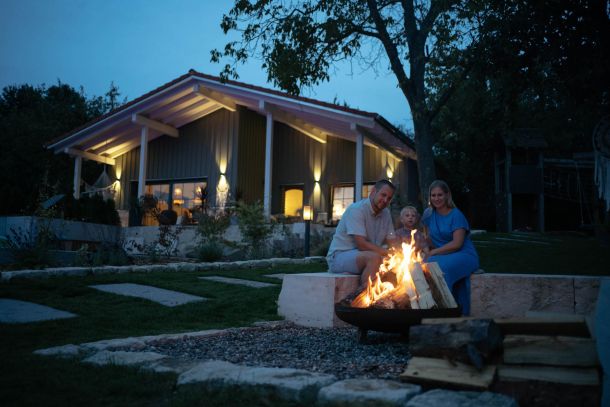 Young family sitting at the barbecue and fire pit in the holiday resort garden